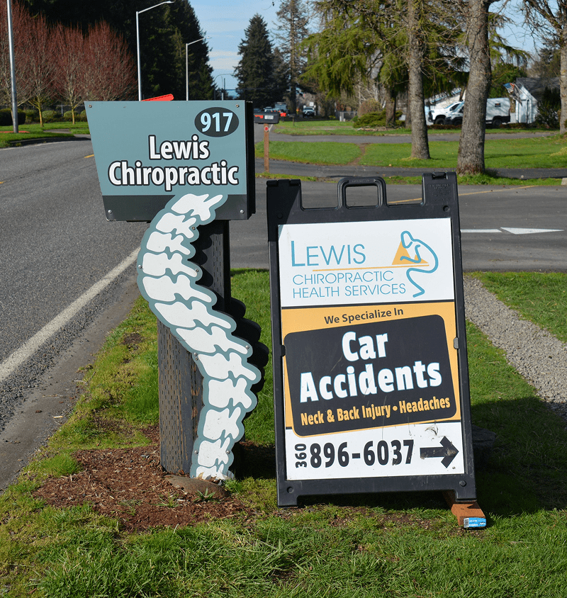 Signs advertising Lewis Chiropractic and car accident services on a street corner.