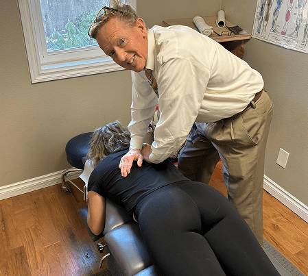 Chiropractor adjusting a patient's back in a clinic.