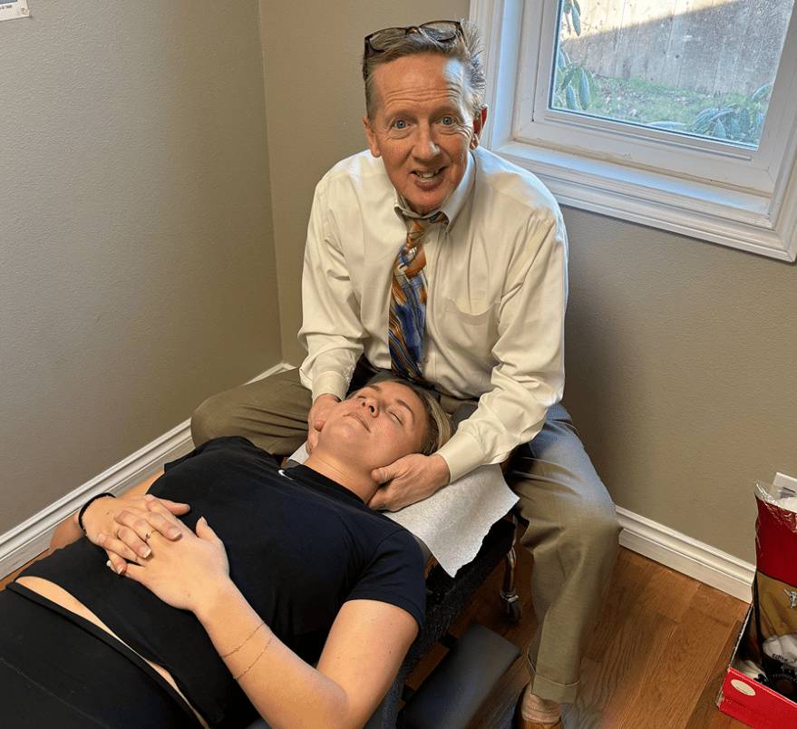 Chiropractor adjusting a patient's neck in a clinic room.