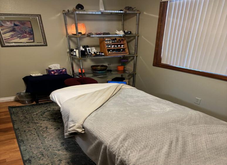 Cozy massage room with a neatly made table and soft lighting.