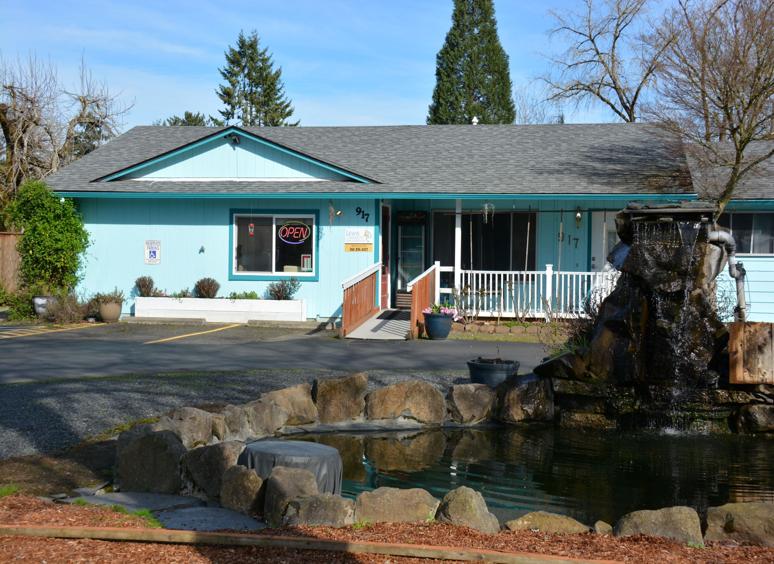 Cozy blue house with a stone water feature in the front yard.